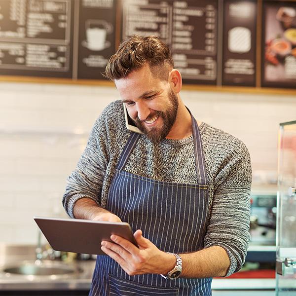 Coffee barista on the phone to his accountant while using a tablet