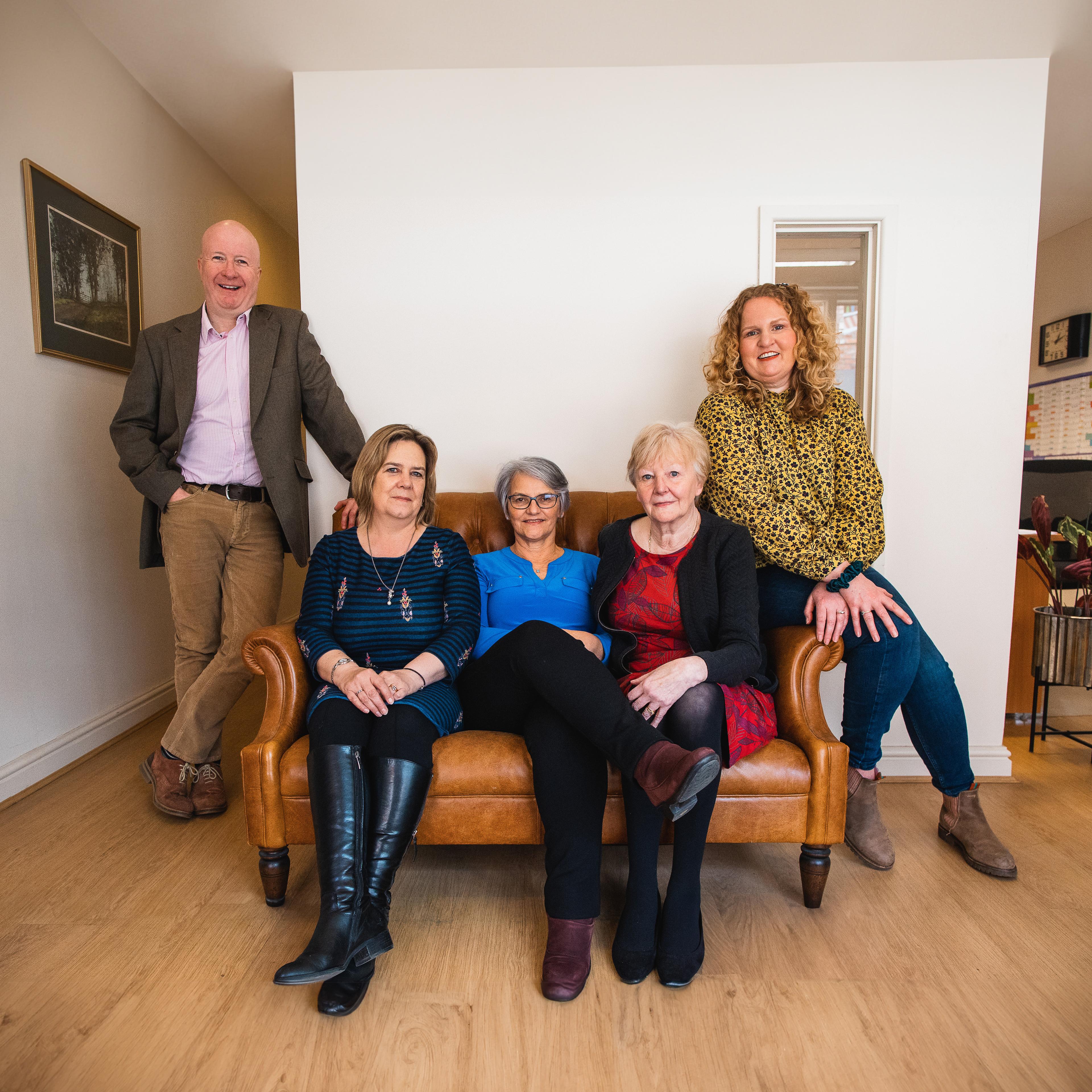 The Arcus team on and around a sofa in the office